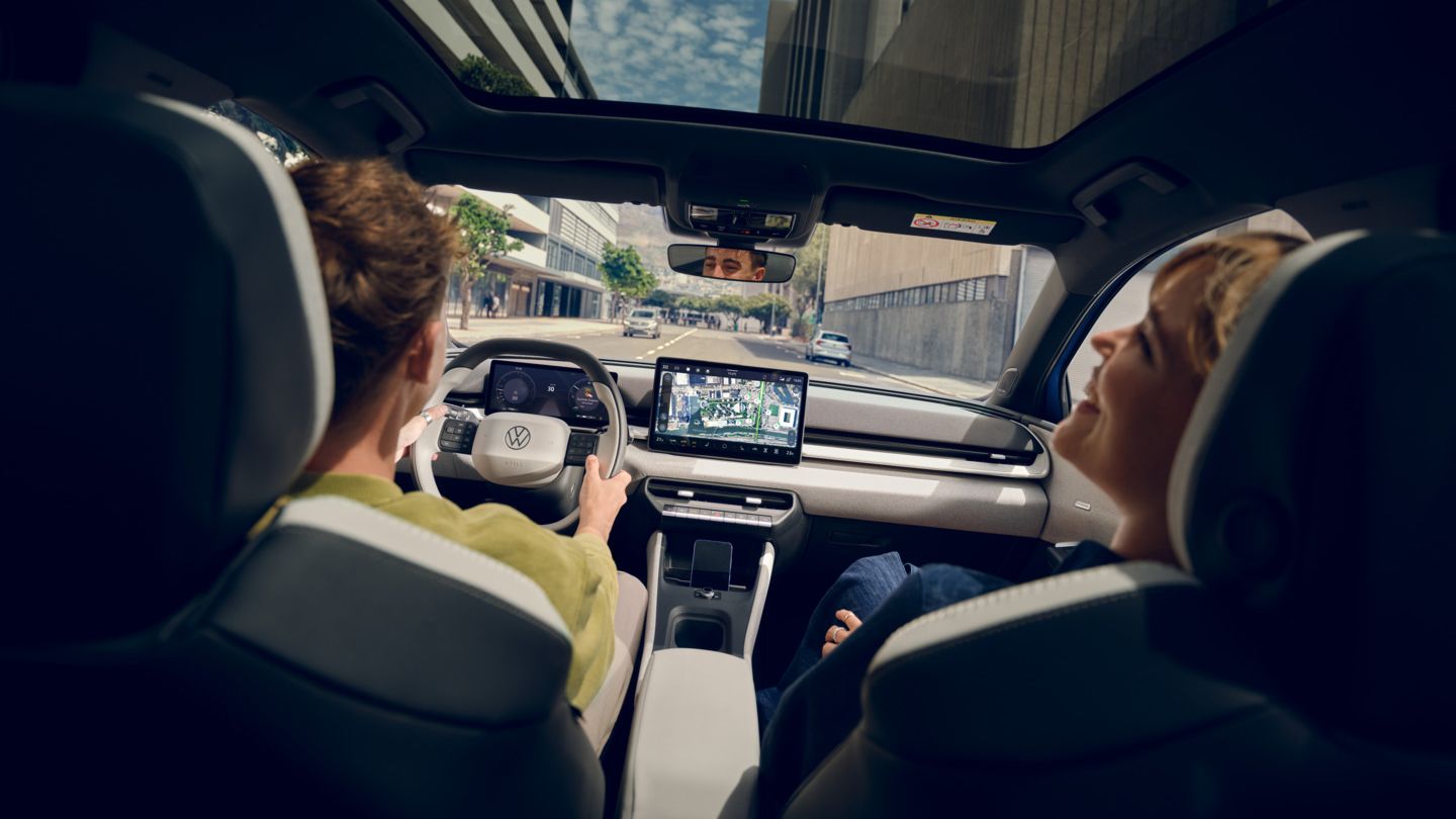 Ein Mann fährt einen VW ID. Polo Style, auf dem Beifahrersitz eine Frau die lacht. Durch das Panoramadach sind Hochhäuser zu sehen