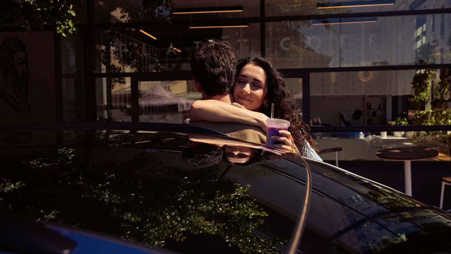 Zwei Personen umarmen sich hinter dem ID.4. 