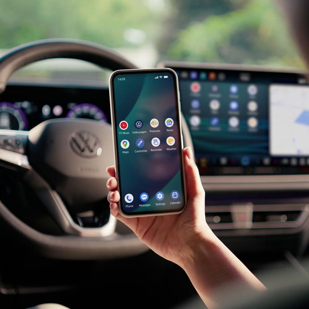 Žena sedí na sedadle řidiče a přes App-Connect zrcadlí svůj chytrý telefon na displeji vozidla.