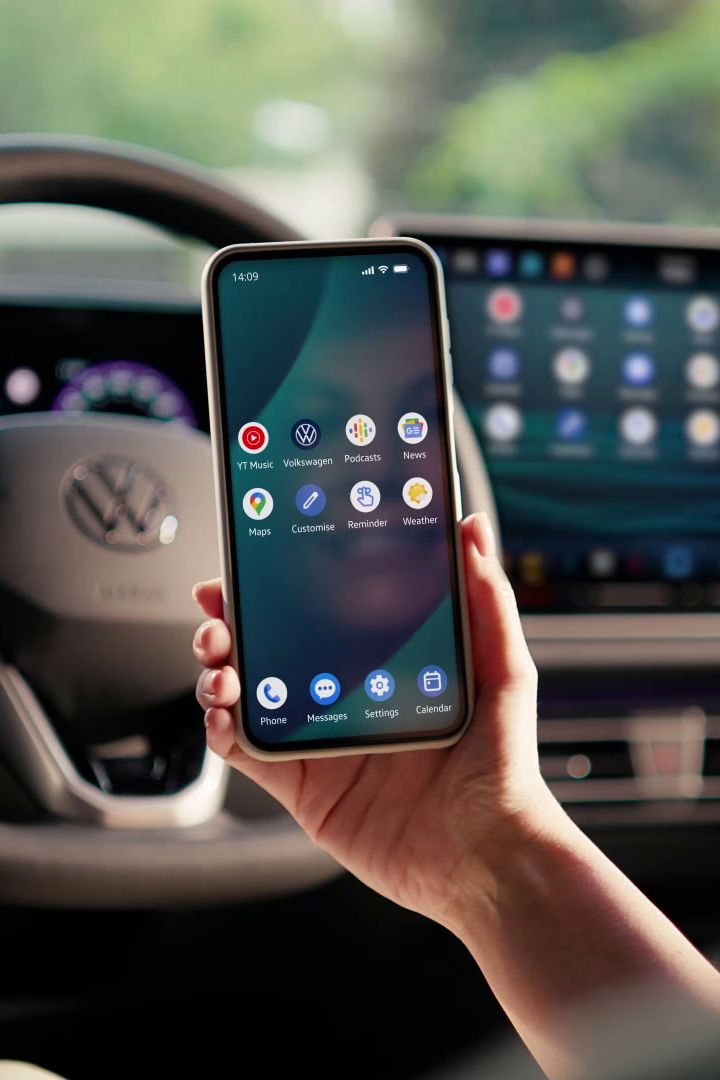Žena sedí na sedadle řidiče a přes App-Connect zrcadlí svůj chytrý telefon na displeji vozidla.