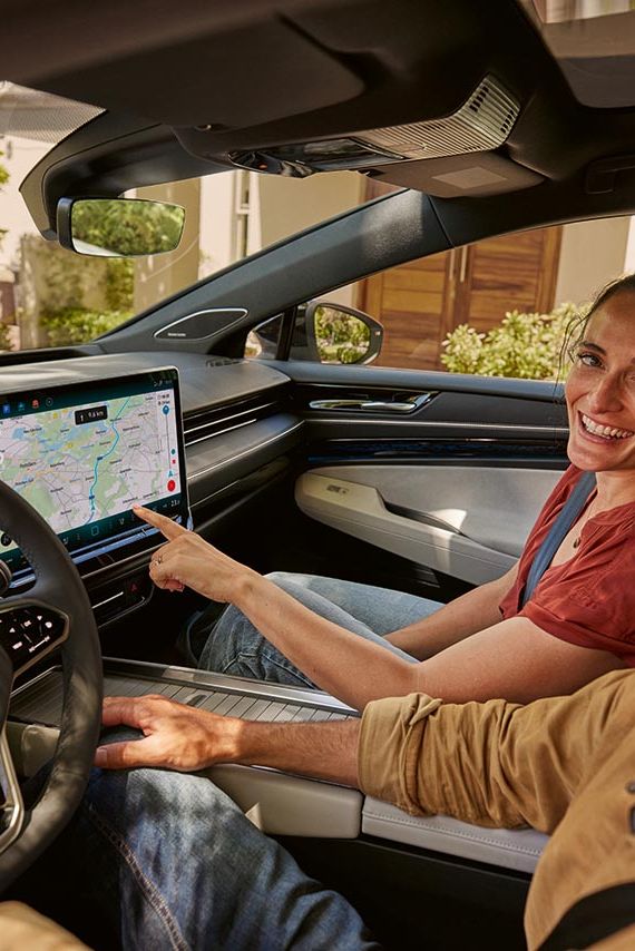Mann und Frau sitzen im VW ID.7 und blicken auf das Display