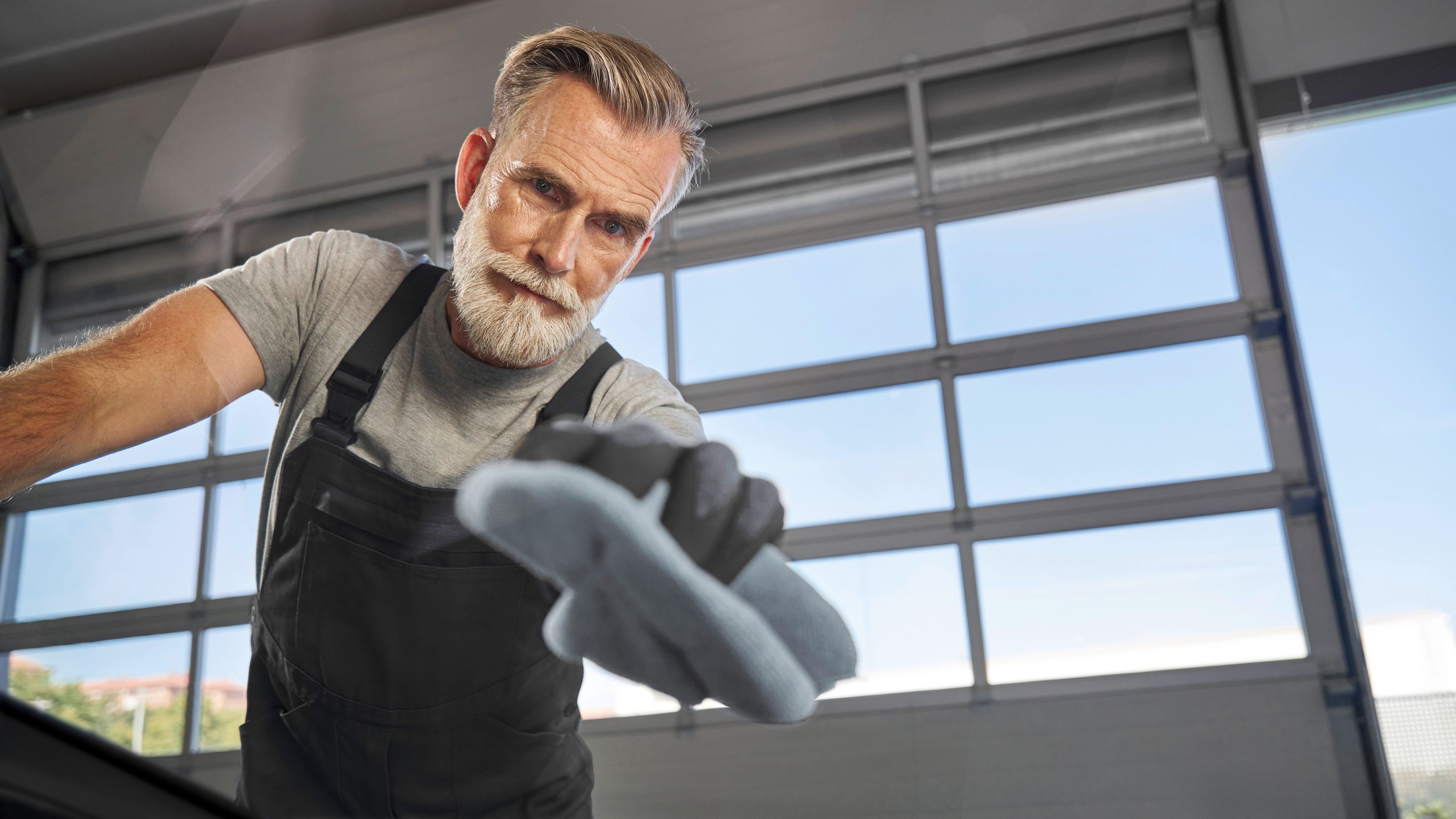 Servisní technik čistící čelní sklo vozu