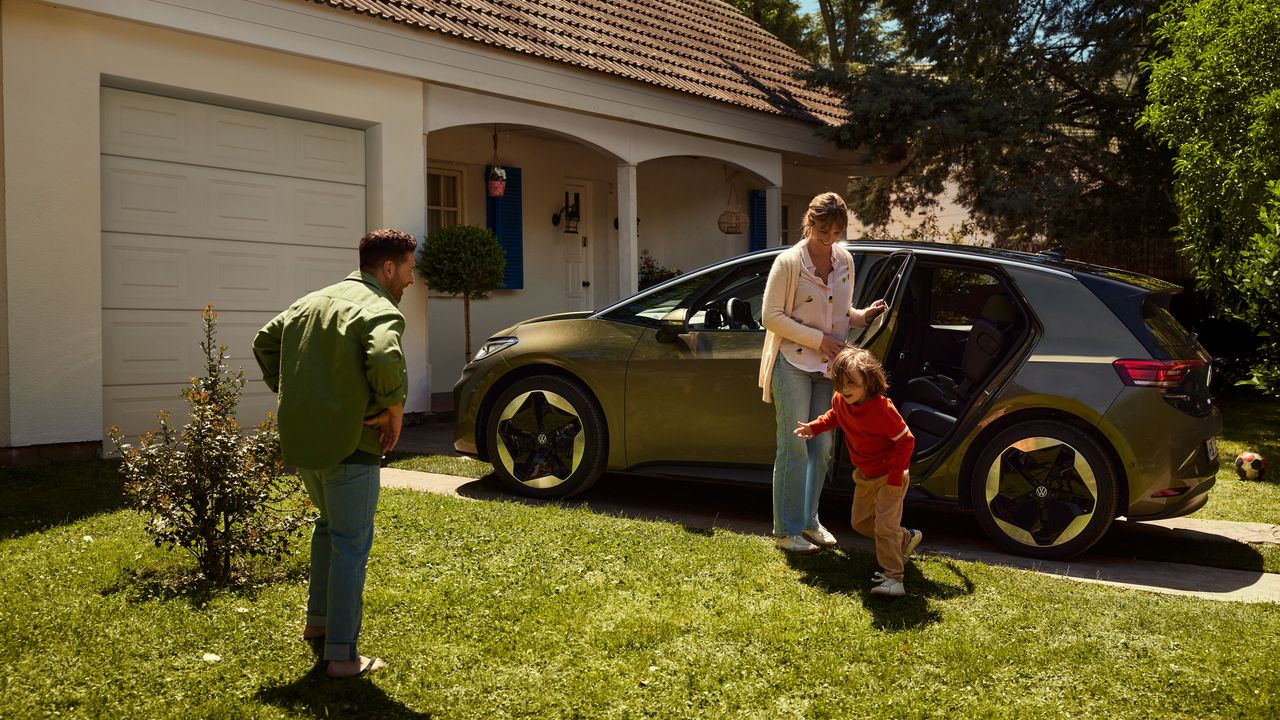 Před obytným domem stojí ID.3. Matka otevírá zadní dveře, zatímco dítě běží po trávníku k otci.