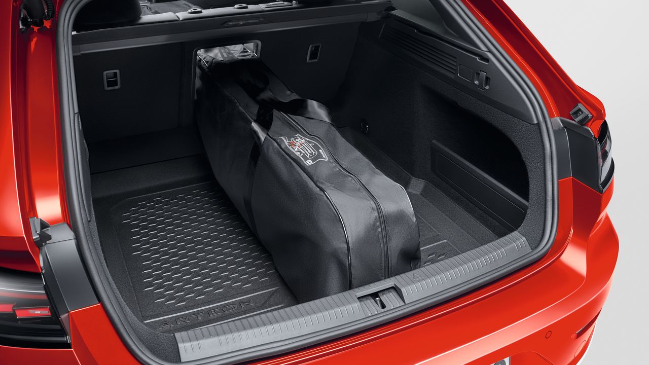 Blick in den geöffneten Kofferraum eines roten Volkswagen. Im Kofferraum befindet sich eine schwarze Volkswagen Skitasche.
