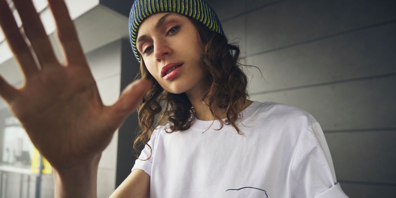 Eine junge Frau mit einem weißen T-Shirt mit aufgedrucktem Golf Logo.