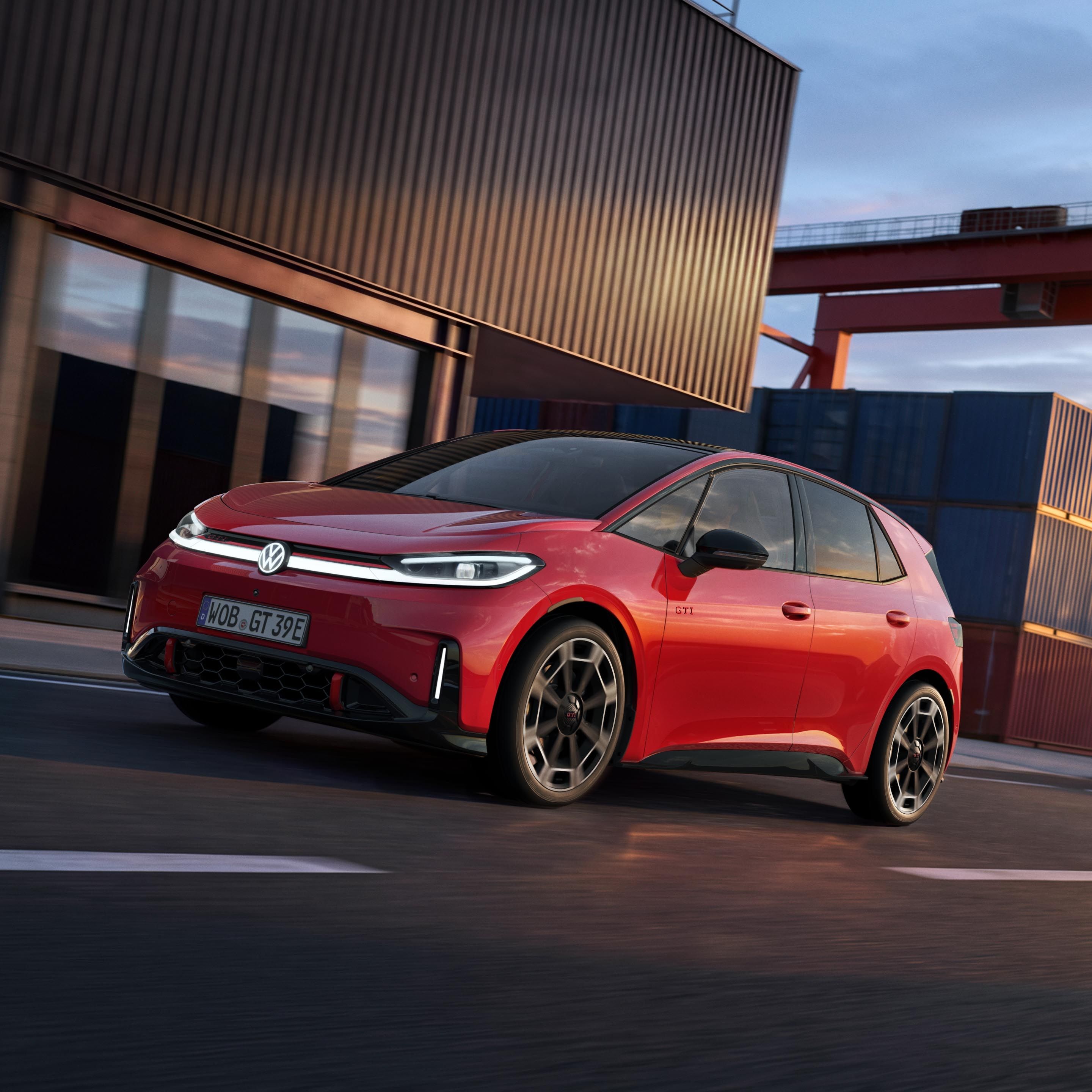 [AI-modified] – Červený VW ID.3 GTI projíždí kolem přístavní budovy se zapnutými světlomety a rozsvíceným logem.
